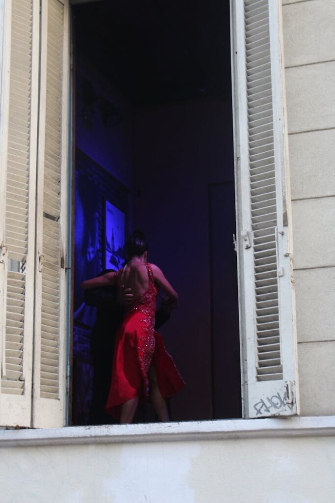 A dancer in a red dress performs tango inside a window in Buenos Aires, Argentina.