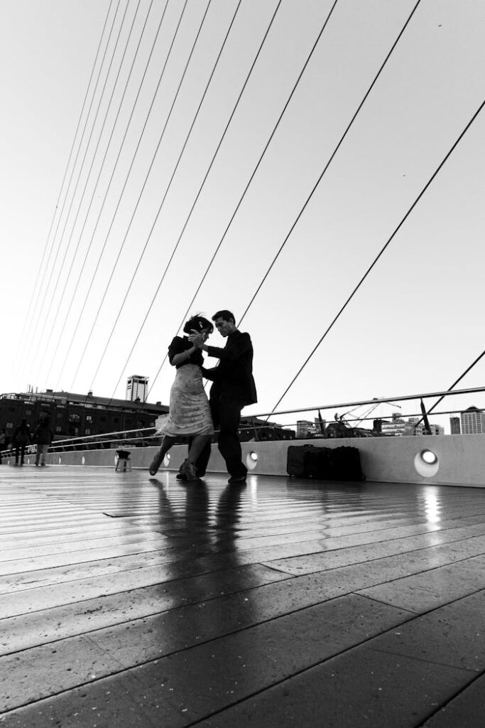 A couple gracefully dances the tango on a famous Buenos Aires bridge, captured in monochrome.